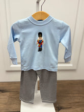 Load image into Gallery viewer, Get your little one holiday-ready with the Boys Nutcracker & Striped Pant Set from Squiggles. This charming ensemble features a light blue long-sleeve tee adorned with a festive Nutcracker applique, paired with coordinating navy and white striped knit pants. Perfectly combining seasonal style with all-day comfort, this set is ideal for family gatherings, holiday photos, or everyday festive fun. Keep your boy cozy and stylish throughout the season with this must-have holiday outfit.