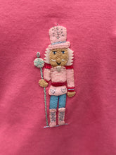 Load image into Gallery viewer, Dress your little one in festive charm with the Girls Applique Nutcracker Ruffle Pant Set by Squiggles. Crafted from soft 100% pima cotton, this set combines comfort with playful style. The bright pink tunic features a delicate pastel Nutcracker applique and a flirty ruffle hem, perfectly complemented by coordinating mint and white striped pants. 
