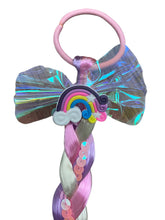Load image into Gallery viewer, Elevate your daughter's style with the Fantasy Braided Ponytail Extension from Anuja Tulia! This playful and colorful ponytail comes with three different styles and colors, complete with a charming detail of either a butterfly, unicorn, or rainbow. Not only is it a fashion statement, but it also supports a great cause, with proceeds going to charity.