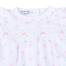Load image into Gallery viewer, Introduce your little one to timeless elegance with this Magnolia Baby smocked bubble. Crafted from luxurious Pima cotton, it's incredibly soft and breathable for delicate skin. The hand-smocked chest features charming pink bows, while delicate pink picot trim adorns the neckline and sleeves for a refined finish. 