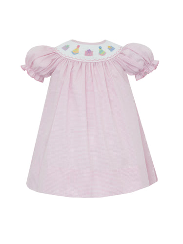 Celebrate your little one’s special day in style with the Girl's Pink Gingham Birthday Smocked Dress by Petit Bebe. This charming dress showcases a pink and white gingham design, adorned with a delicate smocked collar and embroidered birthday hats and gifts. Ideal for making your sweet girl’s birthday truly unforgettable!