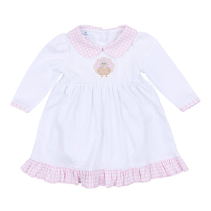 Dress your little one in festive charm with the Pilgrim Pals Applique Collared Dress by Magnolia Baby. Crafted from soft pima cotton, this dress ensures gentle comfort for delicate skin. The pink and white check collar adds a classic touch, while the adorable turkey "Pilgrim" applique brings a playful Thanksgiving spirit. Perfect for celebrating the season in style, this dress combines softness and sweetness for your infant girl’s special moments. Diaper cover is included.