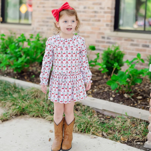 Dress your little one in festive charm with the Ellery Girls Dress in the Cowboy Christmas print by Lila & Hayes. Crafted from soft, breathable pima cotton knit, this long sleeve dress features a delicate ruffled yoke collar and a drop waist accented by a playful tie tassel. Elastic ruffled cuffs add a refined touch while ensuring comfort. Adorned with whimsical boots and Santa motifs, it’s the perfect holiday outfit for joyful celebrations and lasting memories.
