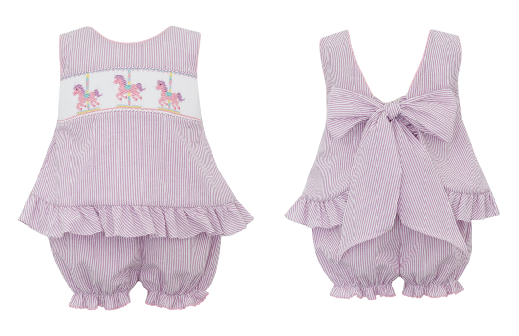 The Girl's Carrousel Bishop Bloomer Set from Anavini combines timeless charm with delicate craftsmanship. Featuring a lilac and white striped bishop tunic adorned with hand-smocked carousel detailing, this set is completed with matching bloomers that showcase elegant ruffles and a sweet tie-back design. Perfectly tailored for infants and toddlers, it offers both comfort and style for your little one’s special moments. Elevate your child’s wardrobe with this beautifully crafted ensemble that captures innocen
