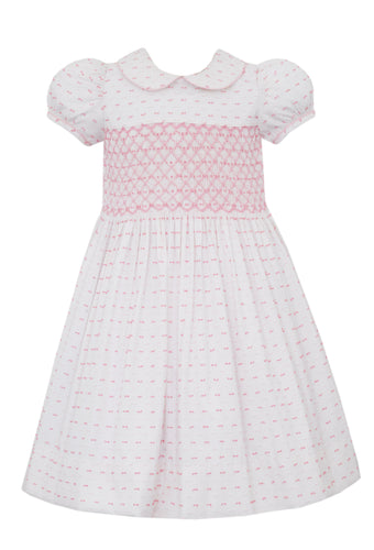 Elevate your little girl's summer wardrobe with our Girls Pink & White Dotted Plumeti Dress. With a smocked bodice and delicate hot pink dots on a crisp white background, this dress exudes timeless style and charm. Perfect for any occasion, its classic plumeti fabric is sure to make her stand out.