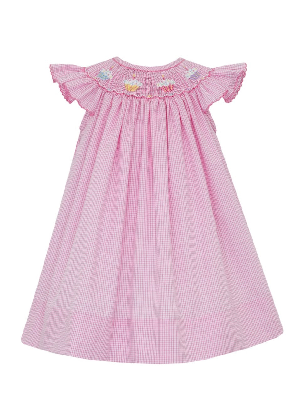 Dress up your little girl in our Girl's Cupcake Smocked Bishop Dress by Petit Bebe. This charming pink and white gingham dress is adorned with delightful cupcake smocking, making her look sweet as can be!