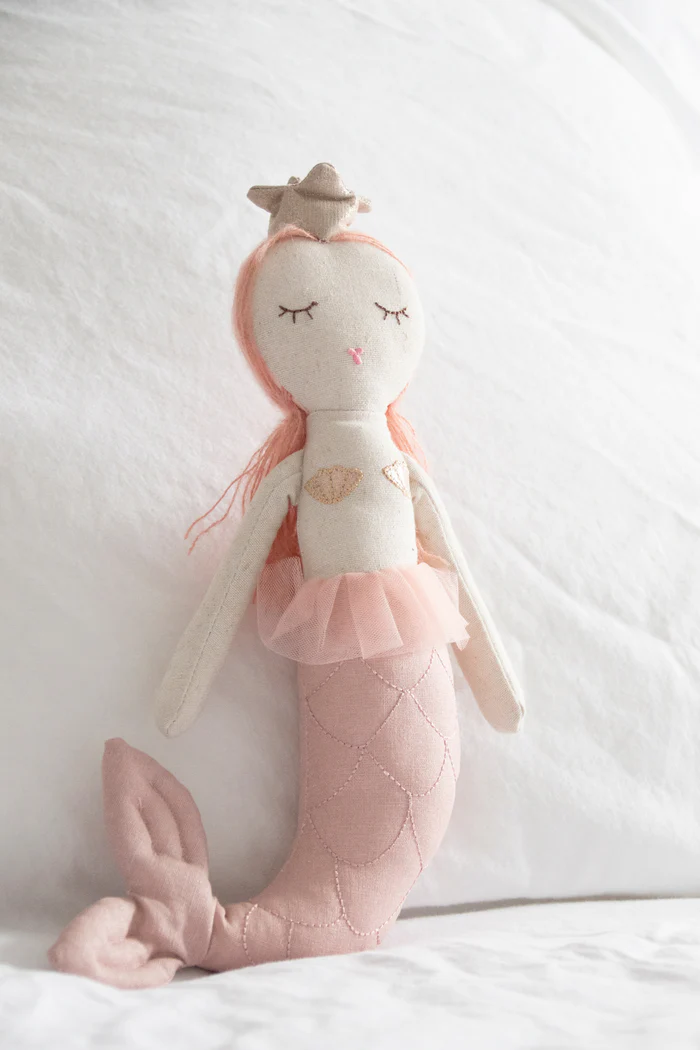 This Mermaid Doll from Great Pretenders is a handcrafted doll, embellished with soft glitter tulle, metallic knits, mo-hair locks, yarn detailing and fanciful expressions / embroidered details. These soft-bodied dolls are perfect for keeping secrets, confiding wishes in, and becoming friends with little ones of all ages. Collectable and Timeless! Approx. 12