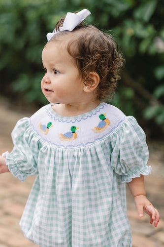 Dress your little one in timeless charm with the Smocked Bishop Riley Mallard Romper by Shop Teeta. Featuring a classic green and white gingham check, this romper is adorned with delicate smocking at the neckline and detailed embroidered mallard ducks, adding a sweet and playful touch. Perfect for coordinated family moments, it also pairs beautifully with matching sibling styles. This piece combines traditional design with exceptional craftsmanship, making it an irresistible choice for any special occasion 