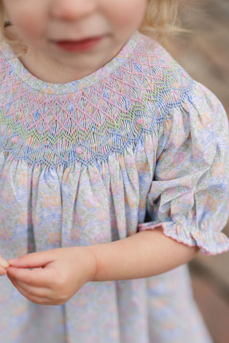 The Smocked Pumpkin Floral Analisa Bishop Bubble from Shop Teeta combines charming fall florals with a delicate smocked neckline, creating an adorable look for infant girls. Its playful bubble silhouette allows for comfortable movement while showcasing a timeless design perfect for any autumn occasion. This piece offers both style and softness, making it a must-have for your little one’s wardrobe.