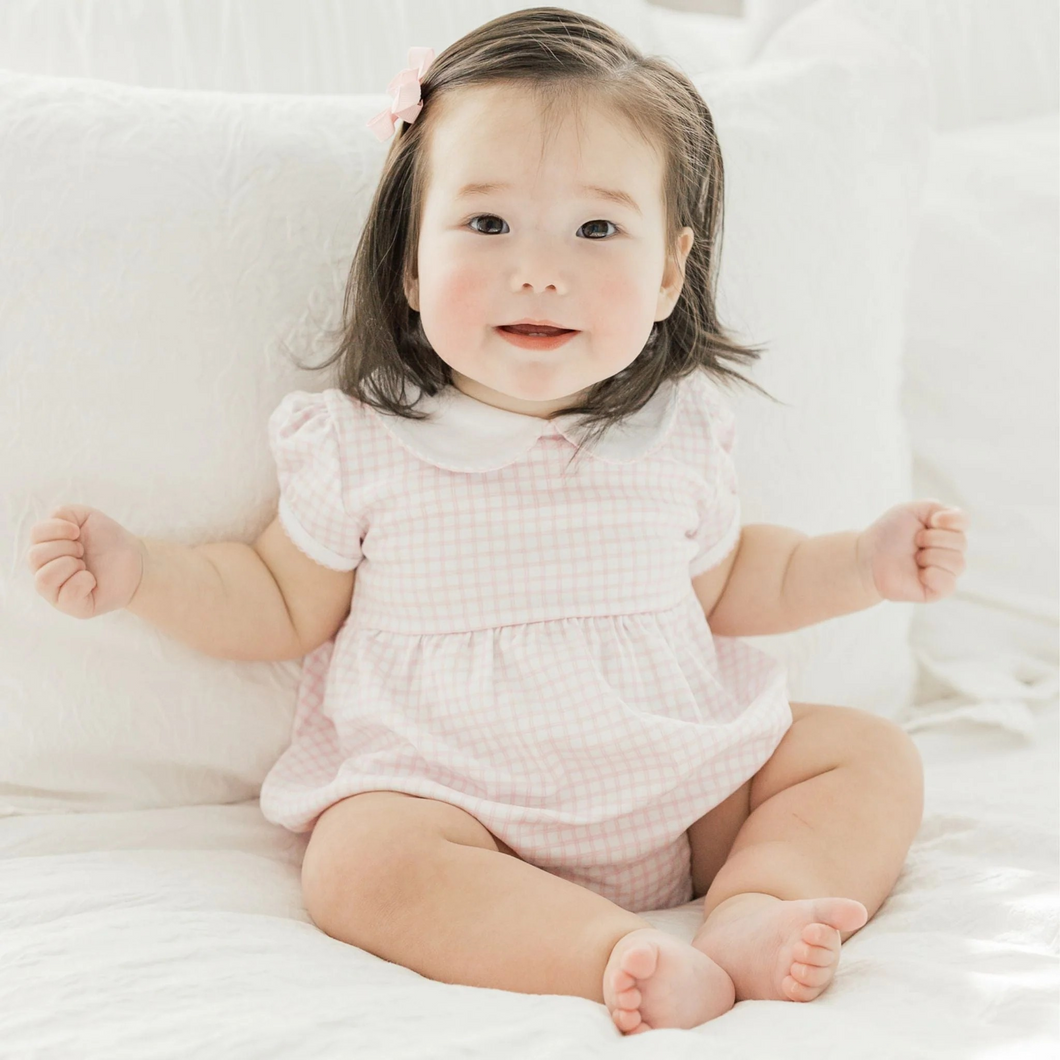 Celebrate precious moments in this Magnolia Baby Peek-A-Boo Wishes Collared Bubble, designed in soft pink with luxurious Pima cotton that feels gentle against delicate skin. The charming check pattern and delicate picot trim create an effortlessly elegant look perfect for family gatherings and special visits. Ready for personalization, this bubble becomes a treasured keepsake when adorned with monograms or embroidery—transforming everyday wear into a one-of-a-kind heirloom your little one will cherish for y