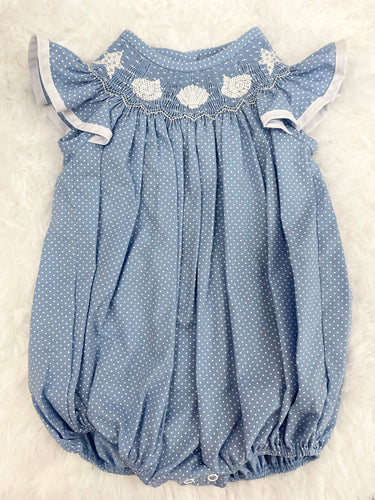 Indulge in seaside charm with the Seashell Smocked Bishop Bubble from Cape Clothing Co. This adorable infant bubble features a playful blue and white pin dot design, complete with a smocked neckline adorned with seashell accents. Perfect for beach adventures and summer photoshoots!