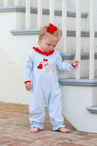 Introducing the Trotter Street Kids Infant Girls Puppy Love Ruffle Romper! This adorable romper is the perfect addition to your little one's wardrobe. Made with soft, light blue striped fabric and featuring cute red accents and an appliqué of a puppy holding a heart, your baby will be both comfortable and stylish.
