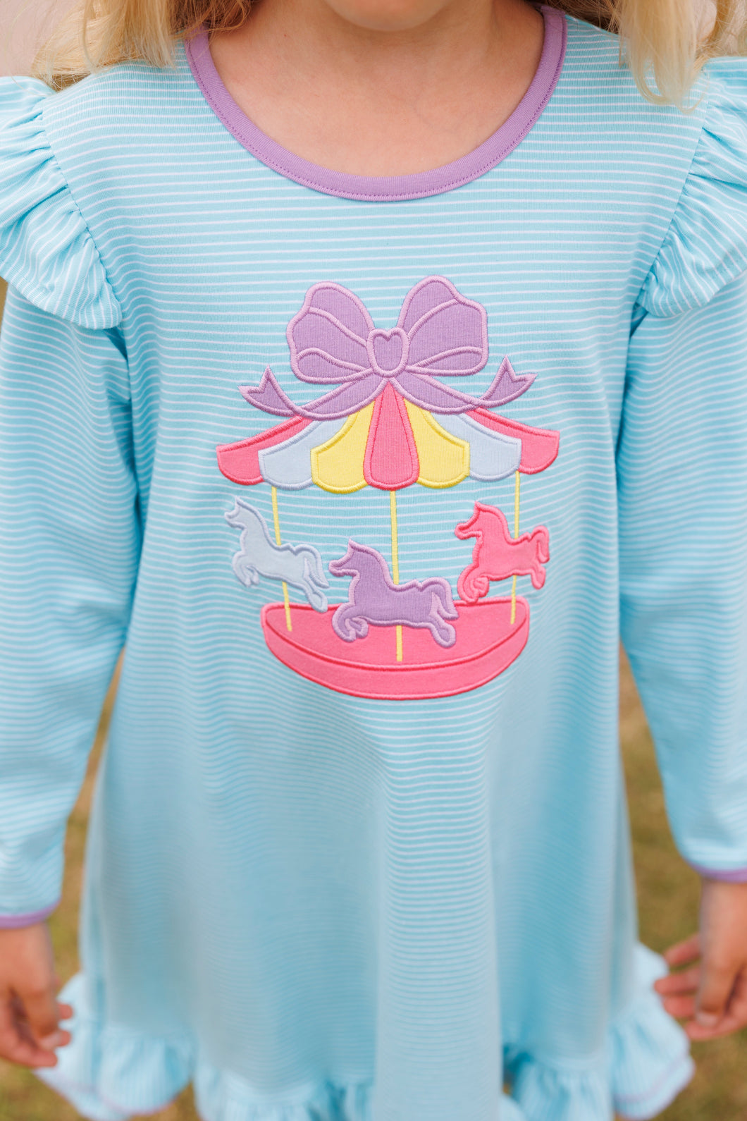 Girls Ruffle Carousel Dress from Trotter Street Kids. Crafted from soft cotton, this aqua and white striped dress features charming ruffle details on the hem and shoulders for a playful, feminine touch. The sweet carousel applique adds a whimsical finish.