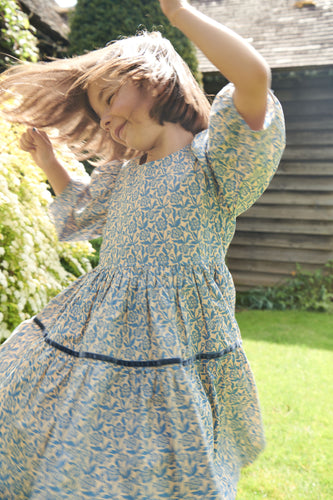 Girls Blue Floral Maribelle Dress from Pink Chicken. With three-quarter puffed sleeves and a full skirt that's tailor-made for twirling, this classic silhouette is accented with a navy velvet taping and a glitter button closure on back. This playful floral print will have her twirling all season!