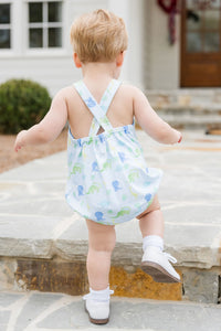 Experience endless adventures with the Louie Dinosaur Knit Bubble from James &amp; Lottie! This charming bubble features a soft blue background and vibrant dinosaur print, perfect for your little one's summer wardrobe. The crisscross strap adds an extra touch of charm to this must-have piece.