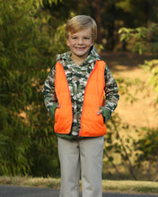Load image into Gallery viewer, Stay ready for fall adventures with the Boys Delta Valley Vest from The Yellow Lamb. This reversible vest features vibrant orange on one side and woodland camo on the other, offering versatile style for boys who love the outdoors. Lightweight yet warm, it’s perfect for layering during crisp autumn days, keeping your little one comfortable and visible on every trail. Durable and easy to wear, this vest combines practicality with fun, making it an essential piece for active boys this season.
