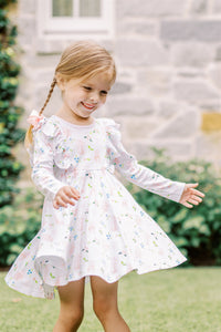 The Girls En Pointe Twirl Dress from The Proper Peony features a soft knit fabric adorned with an elegant ballet and bow print. Its charming ruffle detail and flowy design invite endless twirling, making it perfect for a day filled with dance and delight. Comfortable and stylish, this dress is sure to inspire her graceful moves and joyful moments.