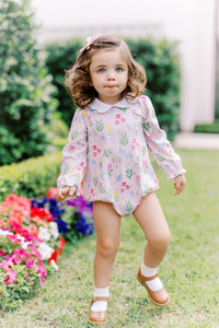 The English Garden Long Sleeve Bubble from The Proper Peony combines comfort and charm with its soft knit fabric and vibrant pastel floral print on a gentle pink background. Featuring a delicate scalloped white collar, this bubble romper adds a touch of casual elegance to your infant girl's wardrobe, perfect for everyday wear or special occasions.