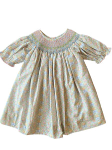 The Smocked Pumpkin Floral Analisa Bishop Dress from Shop Teeta combines charming fall florals with a delicate smocked neckline, creating an adorable look for infant girls. Its playful A-line silhouette allows for comfortable movement while showcasing a timeless design perfect for any autumn occasion. This piece offers both style and softness, making it a must-have for your little one’s wardrobe.