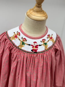 Dress your little one in festive charm with the Girls Rockin' Reindeer Bishop Dress from Cape Point Clothing Co. This vibrant red and white gingham dress features a smocked neckline adorned with playful dancing reindeer and Santa motifs, perfectly capturing holiday joy. The dress style offers a comfortable yet stylish fit, making it ideal for holiday gatherings or special occasions. Celebrate the season in a look that’s both adorable and timeless.