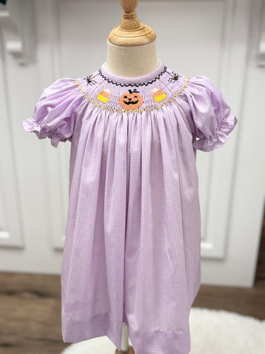 Celebrate the season with the Spooky Season Smocked Bishop Dress by Cape Point Clothing. This charming purple and white gingham dress showcases a beautifully smocked neckline embroidered with playful Halloween motifs, adding a festive touch to your little one’s wardrobe. Perfect for seasonal gatherings and photo moments, it combines classic style with holiday fun to create an unforgettable look this spooky season