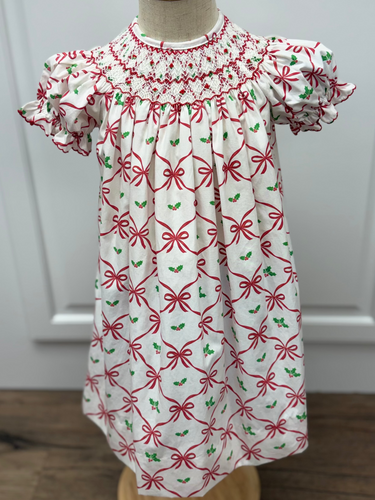 Celebrate the season in timeless elegance with this charming Girl's Alison Holiday Bows Bishop Dress from Anavini. Featuring a festive red bows design paired with mistletoe holly accents, this toddler dress captures holiday magic with sophisticated style. The signature smocked bishop neckline adds a classic, heirloom-quality touch that makes it perfect for special occasions, family photos, and holiday gatherings. 