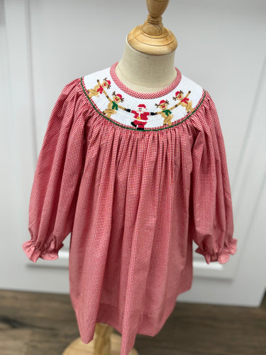 Dress your little one in festive charm with the Girls Rockin' Reindeer Bishop Dress from Cape Point Clothing Co. This vibrant red and white gingham dress features a smocked neckline adorned with playful dancing reindeer and Santa motifs, perfectly capturing holiday joy. The dress style offers a comfortable yet stylish fit, making it ideal for holiday gatherings or special occasions. Celebrate the season in a look that’s both adorable and timeless.
