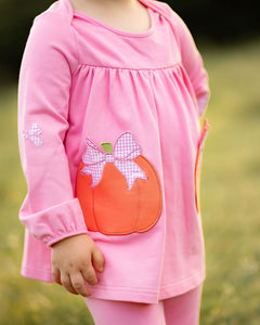 Dress your little one in festive charm with the Pumpkins Tabby Tunic and Legging Set from The Yellow Lamb. This bright pink outfit features playful pumpkin appliques as pockets and delicate bow accents, perfect for celebrating fall and Halloween in style. Comfortable and cute, it’s ideal for keeping her cozy and picture-ready at every seasonal event.