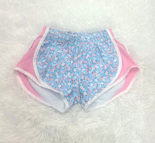 Transform your girl’s summer wardrobe with our Blue Floral Shorts by Funtasia Too! These track shorts feature a stunning blue floral print with contrasting pink sides, adding a touch of feminine charm to athletic looks. Perfect for any activity, these shorts offer both style and functionality.
