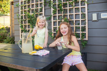 Load image into Gallery viewer, Squeeze the day in the PRODOH Girls' Beach Cruiser Short in Pink Frosting Lemon Stripe. Designed for sunshine and splash time, these girls UPF shorts pair quick-dry comfort with playful lemons for a sweet coastal look. The stretchy 95/5 fabric moves with her, a built-in brief adds coverage, and the secure back pocket keeps treasures close—from shells to hair ties.
