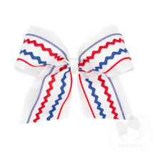Load image into Gallery viewer, Full of patriotic spirit and cheer-ready style, this linen bow features a bold red, white, and blue ric-rac layer atop a crisp linen underlay. Available in red or white and in Medium or King sizes, it’s a standout look for parades, parties, team events, and every star-spangled celebration of the season. This bow is sure to stay in her hair all day with our patented WeeStay™ no-slip hair clip.
