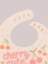 Load image into Gallery viewer, Keep your baby’s clothes clean and dry during feeding time with a nontoxic, food-grade Silicone Bib from JuJuBe × Studio Oh! Made for babies 4 months and older, these bibs feature a deep front pocket to catch messes, and because they are dishwasher-safe, cleanup is fast and easy! Designed to fit comfortably and stay put, each bib features four ouch-free fasteners at the back of the neck strap, so it will stay comfortable as your baby grows.
