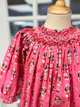 Load image into Gallery viewer, Cape Point Clothing Co.’s Nutcracker Bishop Bubble enchants with festive nutcracker prints and delicate white and red smocking, wrapping your infant girl in warmth and holiday spirit. Perfect for chilly Christmas days, this charming outfit blends comfort with timeless celebration.

