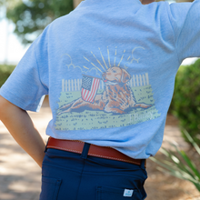 Load image into Gallery viewer, The J Bailey Boys Retriever on Heathered Blue Tee combines Southern charm with everyday comfort. This soft cotton-blend tee features a cheerful retriever clutching the US flag, perfect for young dog lovers and outdoor enthusiasts. Ideal for weekend adventures, casual play, and warm-weather style.
