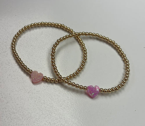 Single Heart Beaded Opal Bracelet from Bara Boheme. Crafted with 14k gold-filled components that resist water damage, this piece is built to withstand your active lifestyle. The heart charm showcases a mesmerizing light or bright pink opal, adding a touch of natural beauty to your wrist. Hypoallergenic and nickel-free, it's perfect for sensitive skin. Mix and match with other beaded bracelets to create an on-trend stacked aesthetic that's uniquely yours.