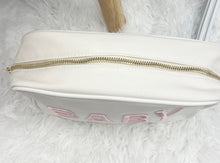 Load image into Gallery viewer, Cream canvas toiletry bag for baby features soft pink BABY embroidery on the front and gold zipper at top. Approx. dimensions: 10&quot; x 3&quot; x&nbsp; 6&quot;. Perfect for any travel bag or diaper bag essentials holder. Makes a great gift for new moms.&nbsp;
