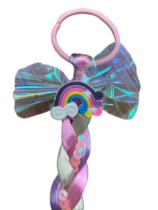 Elevate your daughter's style with the Fantasy Braided Ponytail Extension from Anuja Tulia! This playful and colorful ponytail comes with three different styles and colors, complete with a charming detail of either a butterfly, unicorn, or rainbow. Not only is it a fashion statement, but it also supports a great cause, with proceeds going to charity.