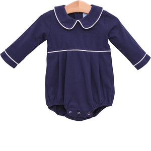 Dress your little one in timeless charm with the Joseph Bubble in Navy from Trotter Street. This classic navy bubble features a delicate Peter Pan collar and crisp white piping, adding a touch of elegance to your infant boy’s wardrobe. Personalize it with a name or monogram to create a cherished heirloom that will be treasured for years to come. Perfect for special occasions or everyday wear, this piece combines style and sentiment beautifully.