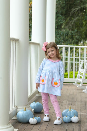 Dress your little one in charming style with the Girls Pumpkin Ruffle Pant Set from Trotter Street Kids. This adorable outfit features a blue and white gingham tunic adorned with playful appliqué pumpkins and delicate ruffles, adding a sweet seasonal touch. Paired with coordinating pink leggings, it offers both comfort and vibrant color coordination, perfect for fall outings or festive gatherings. 