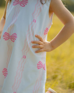 Dress your infant girl in the adorable Ada Ribbons &amp; Bows Dress from The Yellow Lamb. This charming dress features a pink bow and ribbon design and beautiful ruffle neckline detail. Don't forget to grab the matching Ada Ribbons &amp; Bows Bubble for a sibling set!