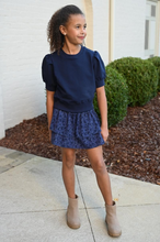 Load image into Gallery viewer, Elevate any outfit with our Riley Sweatshirt in Navy. This short sleeve, ruffle shoulder sweatshirt for tween girls is perfect for pairing with jeans or a skirt. Complete the look with our Scottie Spots Skirt from pleat.
