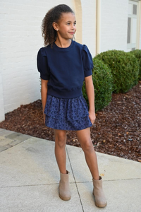 Elevate any outfit with our Riley Sweatshirt in Navy. This short sleeve, ruffle shoulder sweatshirt for tween girls is perfect for pairing with jeans or a skirt. Complete the look with our Scottie Spots Skirt from pleat.