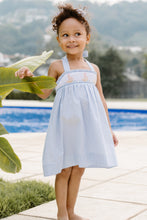 Load image into Gallery viewer, This enchanting Girl&#39;s Rachel Sailboat Stripe Dress captures summer&#39;s essence with classic blue and white seersucker stripes. The beautifully smocked bodice showcases charming embroidered sailboats, while the halter tie design ensures a perfect fit. An irresistible choice for warm-weather adventures, this quintessential summer dress is available for both toddlers and girls. Complete the look with the matching little sister short set for adorable coordinated outfits!
