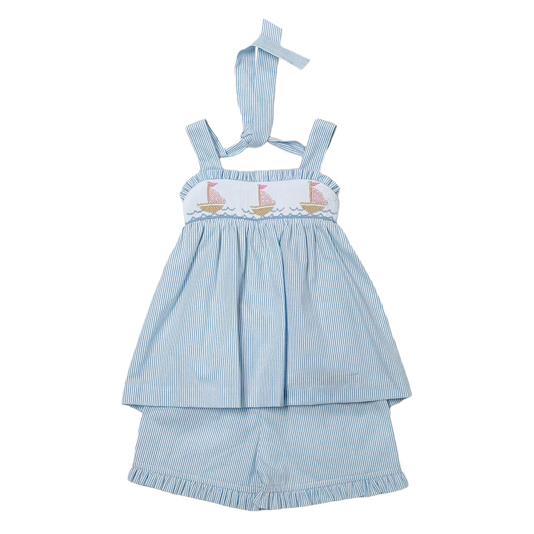 This enchanting Girl's Rachel Sailboat Stripe Short Set captures summer's essence with classic blue and white seersucker stripes. The beautifully smocked bodice showcases charming embroidered sailboats, while the halter tie design ensures a perfect fit. An irresistible choice for warm-weather adventures, this quintessential summer outfit is available for infant girls. Complete the look with the matching big sister dress for adorable coordinated outfits!