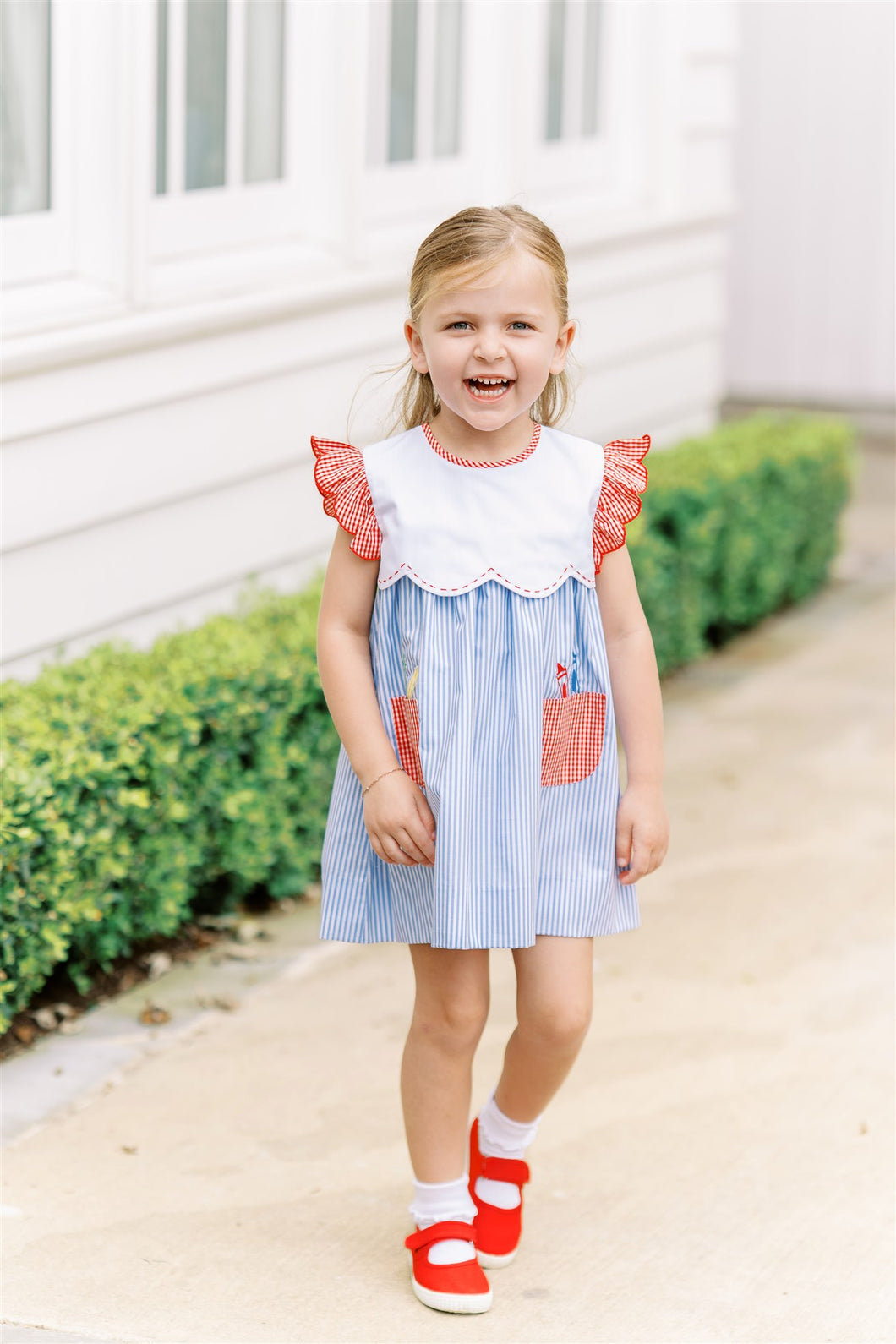 The Girls School Days Dress by The Proper Peony combines classic blue and white stripes with charming stitched crayon accents for a playful yet polished look. Featuring a crisp white collar and delicate ruffle sleeves, this dress is ideal for capturing those memorable back-to-school moments in style. Comfortable and cute, it’s a perfect choice to make your little girl shine on picture day and beyond.