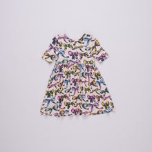 Load image into Gallery viewer, This Girls Bamboo Bows Steph Dress is perfect for little ones, made from soft bamboo material for added comfort. The dress is adorned with adorable bows, adding a touch of sweetness to any outfit. From Pink Chicken, this dress is both stylish and comfortable.

