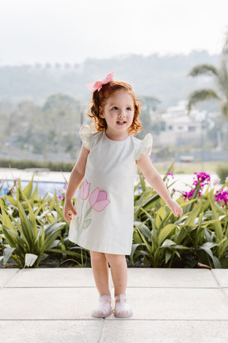 This adorable Sloane Tulip Seersucker Striped Dress from Zuccini Kids is perfect for your toddler girl. The dress features lime green stripes and cute pink tulip appliques, adding a touch of whimsy to her wardrobe. Made with soft and lightweight seersucker fabric, it's perfect for warm weather and playtime.