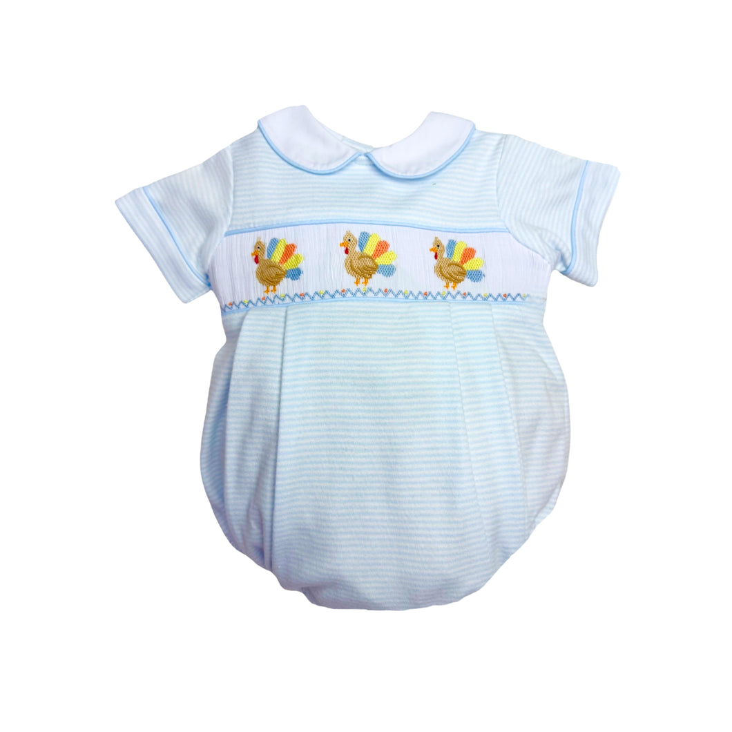 Dress your little one in playful charm with the Infant Boys Turkey Brandon Bubble from Zuccini Kids. Soft blue and white mini stripes create a gentle backdrop for the delightful smocked bubble, featuring colorful embroidered turkeys that add a whimsical touch. Comfortable and stylish, this bubble is perfect for keeping your infant cozy while standing out with unique, eye-catching details this Thanksgiving.