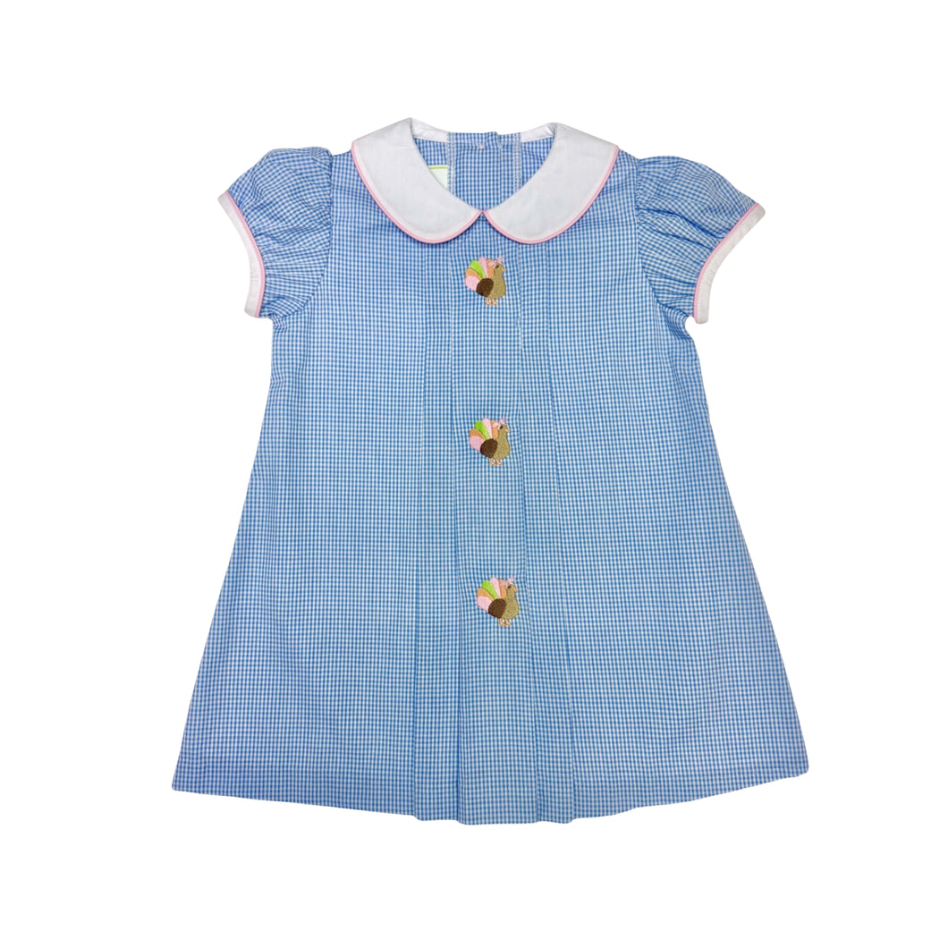 Dress your little one in timeless charm with the Girls Gingham Turkey Robyn Dress from Zuccini Kids. This festive dress features a crisp blue and white gingham pattern, a delicate white and pink piped Peter Pan collar, and a delightful turkey embroidery front and center. Perfect for Thanksgiving celebrations, it combines classic style with adorable holiday spirit, ensuring your toddler girl stands out as the season's little star. Comfortable and cute, it’s the ideal choice for memorable family moments espec