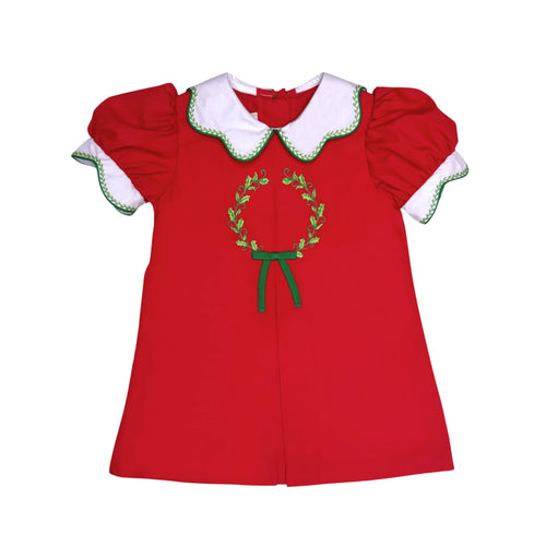 The Girl's Red Wreath Ella Dress from Zuccini Kids combines timeless charm with elegant details. Crafted from soft broadcloth, it features a classic Peter Pan collar and a beautifully embroidered wreath that adds a delicate, festive touch. The pleated front enhances its graceful silhouette, making it perfect for special occasions and cherished moments this Holiday season. 